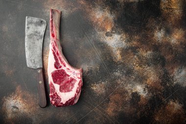 Tomahawk bifteği çiğ set, ve eski kasap satır bıçağı, eski koyu rustik arka planda, üst görünüm düz düz, metin için kopyalama alanı