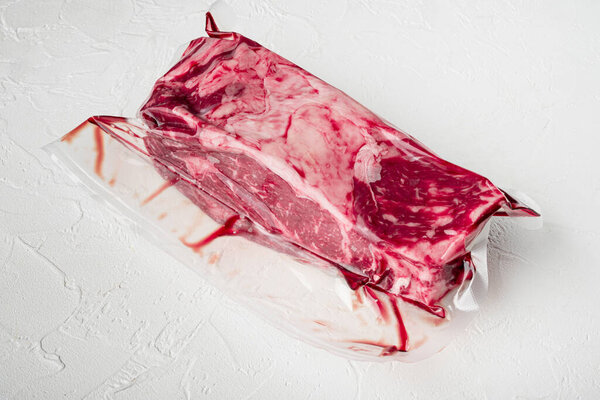 Rib eye marbled beef cut vacuum pack set, on white stone  background, with copy space for text