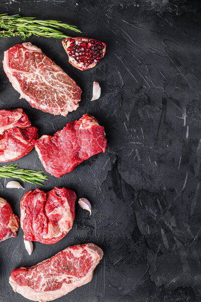 Set of various alternative raw meat steaks  over black background top view. With space for text