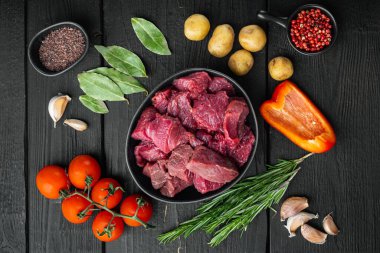 Çiğ organik et ya da kuzu eti ve patates, siyah ahşap arka planda, düz manzaralı.