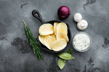 Lezzetli çıtır patates cipsi seti, soslu, gri taştan arka planda, düz manzaralı