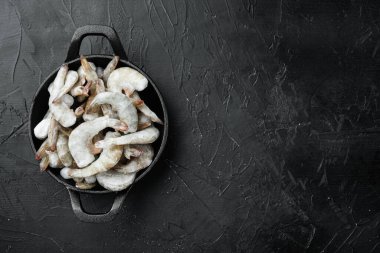 Dondurulmuş çiğ kaplan karidesleri, karidesler, dökme demir tavada, siyah taş arka planda, düz manzaralı, metin için fotokopi alanı