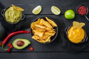 Parti için aperatif, cips, soslu nachos, siyah ahşap arka plan, üst görünüm veya düz yatış
