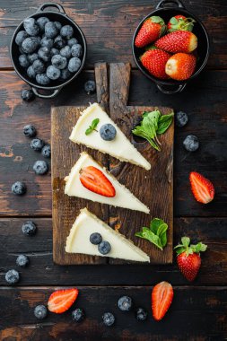 Klasik New York Cheesecake, dilimlenmiş, eski siyah ahşap masa arkaplanı, üst manzara düz.
