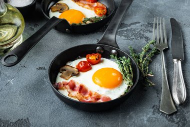 Pastırma ve sebzeli sahanda yumurta, gri arka planda, dökme demir tavada.