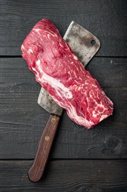 Çiğ mermer biftek entrecote Black Angus Prime et set, filet mignon fileto kesim, eski kasap satır bıçağı ile siyah ahşap masa arka planı, üst görünüm düz, metin için kopya alanı