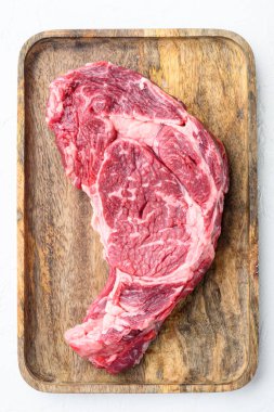 Çiğ pirzola, mermer et, tuz, biberiye ve sarımsak seti, beyaz taş zemin üzerinde, üst manzara düz