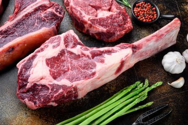 Çiğ sığır eti seti, Tomahawk kesimi, eski koyu kırsal arka planda.