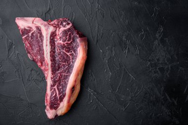 Kuru, eski, kemikli biftek seti, siyah taştan arka plan, düz üst görünüm, metin için kopyalama alanı