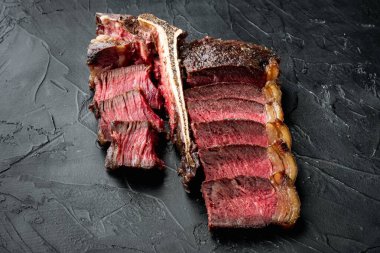 Taze sulu orta pişmiş biftek ve biftek ya da biftekli biftek seti, siyah taş zemin üzerinde, metin için fotokopi alanı ile birlikte.