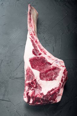 Çiğ pişmemiş siyah angus bifteği kemik setinde, siyah taş arka planda, metin için fotokopi alanı
