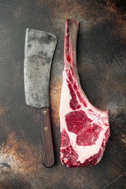 Çiğ baltayla biftek, baharat masajı setiyle ızgara yapmak için malzemeler, ve eski kasap bıçağı, eski koyu kırsal arka planda, üst görünüm düz