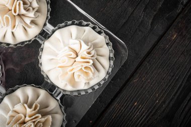 Manti, geleneksel Türk ravioli seti, plastik tepside, siyah ahşap masa zemininde, üst görünüm düz, metin alanı için fotokopi alanı