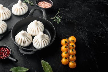 Manti veya Mandy hamur tatlısı, popüler Asya yemeği seti, kızarmış demir tavada, siyah taş zemin üzerinde, üst görünüm düz, metin için kopya alanı ile