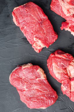 İki çiğ organik biftek, siyah desenli masa manzaralı..