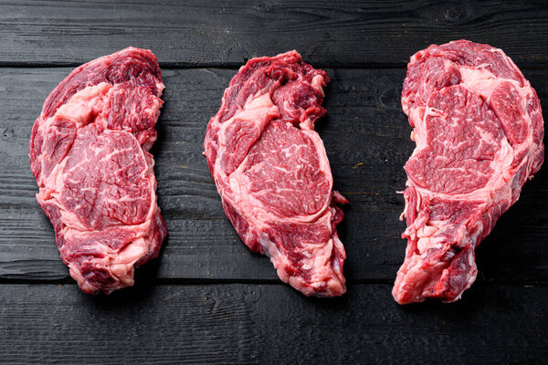 Classic fresh beef striploin steaks set, Rib eye cut, on black wooden table