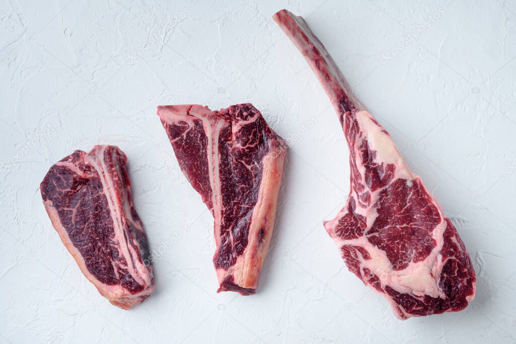 Dry aged marbled beef meat cut set, tomahawk, t bone or porterhouse and club steak, on white stone  background, top view flat lay