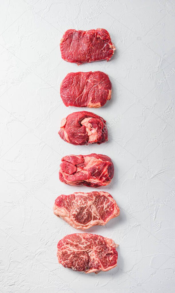 Rraw beef steaks set top blade, rump, chuck eye roll over white concrete background, top view banner size.