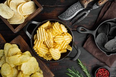 Değişik patates cipsleri seti, eski koyu ahşap masa, üst manzara düz yatıyordu