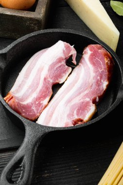 Domuz göbeği çiftliği seti, dökme demir tavada, siyah ahşap arka planda.