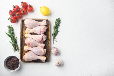 Çiğ tavuk budu seti, biberiyeli, baharatlı ve sebzeli, beyaz arka planda, düz görünüm yatağı, metin için kopya alanı