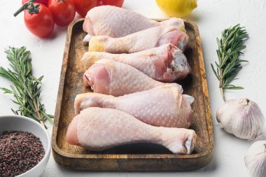 Çiğ tavuk budu, malzemeli bagetler, biberiye, baharat ve sebzeler, beyaz arka planda.