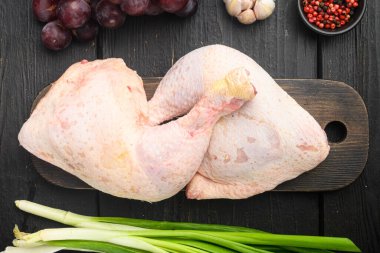 Taze tavuk bacağı ve terbiye malzemeleri seti, ahşap kesim tahtası, siyah ahşap masa, üst görünüm düz