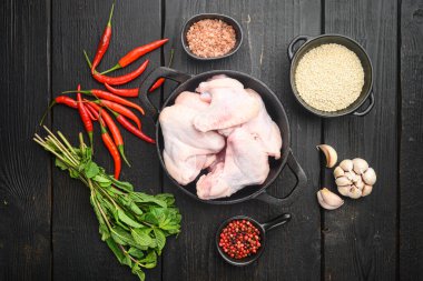 Taze çiğ orta tavuk kanatları, ve susam, kızartma demir tavada, siyah ahşap masa üzerinde, üst düz görünüm