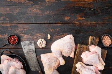 Çiğ tavuk eti fileto, but, kanatlar ve bacaklar seti, baharat, biberiye ve kekik ile eski kasap bıçağı, eski siyah ahşap masa arka planı, düz görünüm, metin için kopya alanı ile