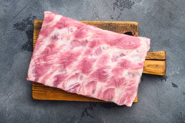 Çiğ domuz eti pirzolası, ahşap kesim tahtasına, gri taş arka planda, üst manzara düz.