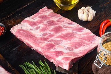 Biberiye ve sarımsaklı taze çiğ domuz pirzolası. Eski, siyah ahşap masa üzerinde.