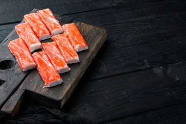 Mavi yüzme yengeci setiyle taze yengeç surimi, ahşap kesim tahtası, siyah ahşap masa arka planı, kopyalanacak yer ve metin için yer