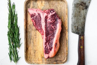 Kurumuş çiğ çiğ kemik veya biftek mermer et. Otlar ve baharatlarla hazırlanmış biftek. Beyaz taş arka planda, düz manzaralı.