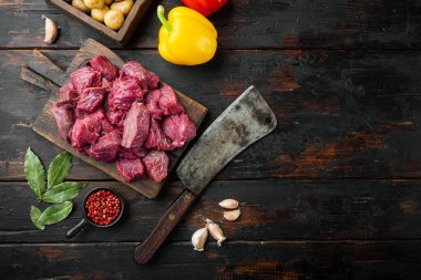 Biftek yahnisi hammaddesi, tatlı dolma biberle hazırlanmış, eski siyah ahşap masa üzerinde, üst görünümü düz, metin alanı için fotokopi alanı ile