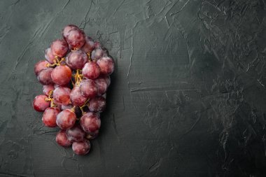 Olgun üzüm seti, koyu kırmızı meyveler, siyah taş zemin üzerinde, üst görünüm düz, metin için kopyalama alanı ile