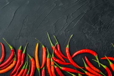 Olgun Cayenne biber seti, siyah taş zemin üzerinde, üst görünüm düz yatay, metin için kopyalama alanı ile