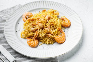 Karides ve pesto soslu makarna, tabakta, beyaz taş yüzeyde.