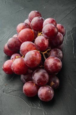 Doğal organik sulu üzümler, koyu kırmızı meyveler, siyah taş arka planda.