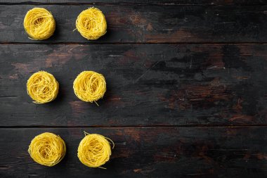 Eğri büğrü İtalyan Tagliolini makarna seti, eski siyah ahşap masa üzerinde, üst görünüm düz, metin alanı için kopyalama alanı ile