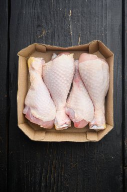 Taze tavuk budu seti, kağıt pakette, siyah ahşap masa zemininde, üst manzara düz yatıyordu.