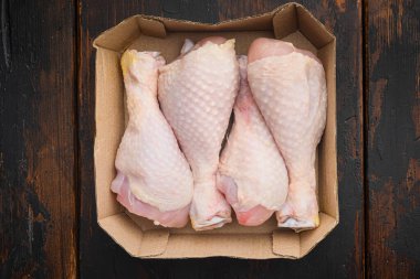 Tavuk eti paketi seti, kağıt pakette, eski siyah ahşap masanın üzerinde, üst manzara düz yatıyordu.