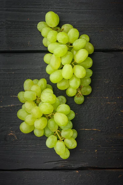 Red and white grapes set, green fruits, on black wooden table, top view flat lay