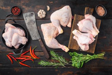 Çiğ tavuk bacağı, baget seti, ve baharat ve şifalı otlar ile eski kasap satır bıçağı biberiye ve kekik, eski siyah ahşap masa arka planı, üst düz yatıyordu