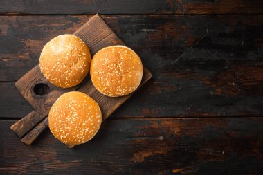 Hamburger ekmeği ev yapımı Brioche Hamburger Çörekleri seti, ahşap servis tahtasına, eski koyu ahşap masa arkaplanına, üst düz manzaralı, metin için kopya alanı olan