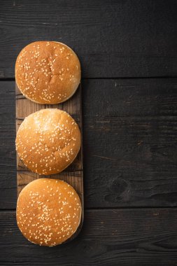 Hamburgerler, ev yapımı susamlı çörekler sandviç seti için köfte köfteler, ahşap servis tahtası, siyah tahta masa arkaplanı, en üstteki düz yatak, metin için kopya alanı