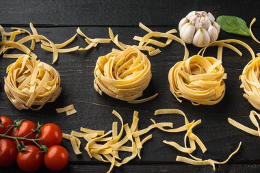 Tagliatelle makarna ve malzeme seti, siyah ahşap masa arka planında