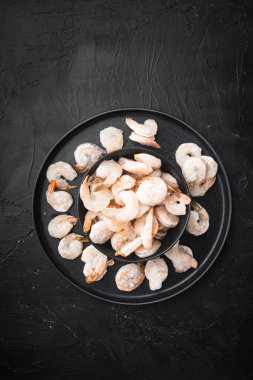 Donmuş soyulmuş haşlanmış karides seti, kasede, siyah taş zemin üzerinde, üst görünüm düz, metin için kopyalama alanı ile