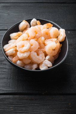 Kaynamış kabuklu karides karidesleri kase içinde, siyah ahşap masa üzerinde, metin için fotokopi alanı ile pişirildi.