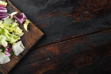 Ispanak, romaine ve marul setiyle taze yeşil salata, ahşap kesim tahtası üzerinde, eski siyah ahşap masa üzerinde, üst düz görünüm, metin için kopya alanı ile