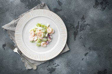Karides, avokado, domates ve mayonez soslu, elma ve üzümlü salata, gri arka planda, düz görünüm